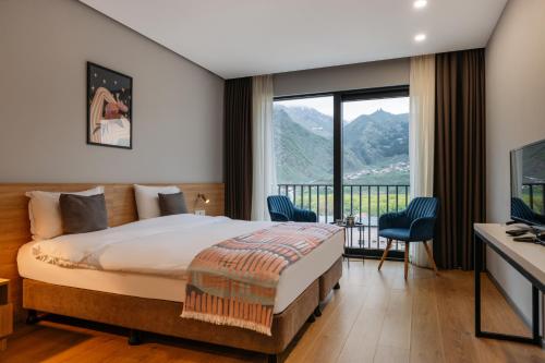 una camera con un letto e una grande finestra di Hotel Memoir Kazbegi by DNT Group a Kazbegi