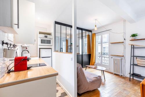 Il comprend une cuisine et un salon avec des murs blancs et du parquet. dans l'établissement GuestReady - Bel Apt. dans le 17ème, à Paris