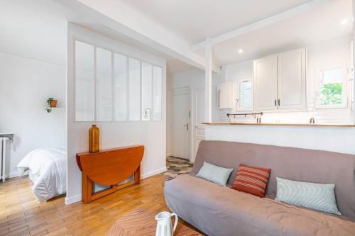 un salon avec un canapé et une cuisine dans l'établissement GuestReady - Bel Apt. dans le 17ème, à Paris