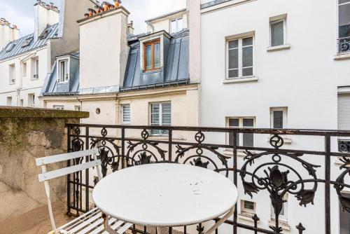 - une table blanche sur un balcon avec des bâtiments dans l'établissement GuestReady - Bel Apt. dans le 17ème, à Paris