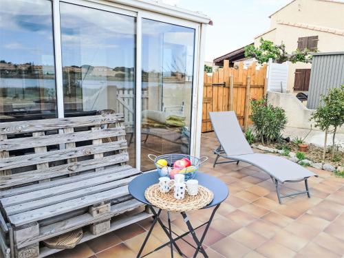 une terrasse avec un banc, une table et des chaises dans l'établissement Holiday Home Belle Ile 1 by Interhome, à Gruissan