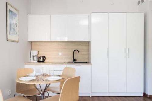 a kitchen with white cabinets and a table with chairs at Baltic Apartments in Pobierowo