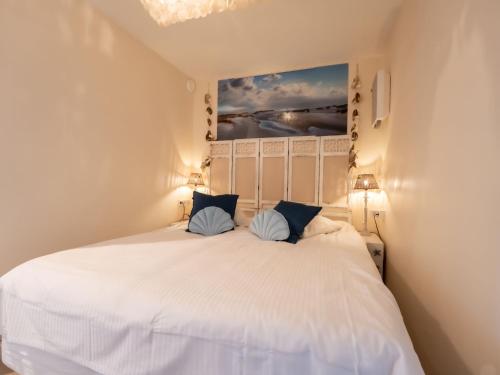 une chambre avec un lit blanc avec des oreillers bleus dans l'établissement Studio Pacific with parking and sea view by Interhome, à Blankenberge