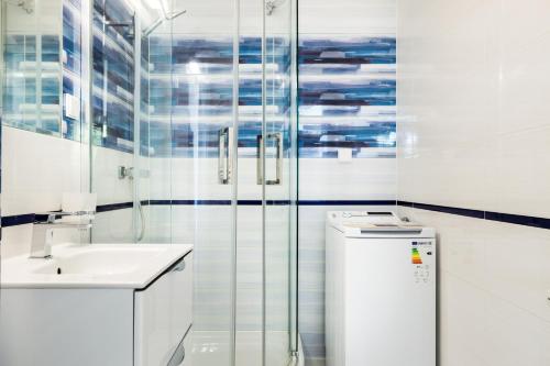 a white bathroom with a sink and a shower at Baltic Apartments in Pobierowo