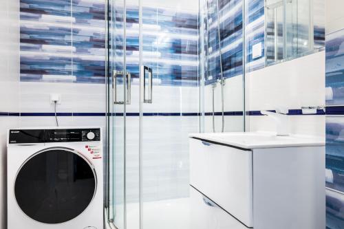 a washing machine in a white bathroom with a sink at Baltic Apartments in Pobierowo