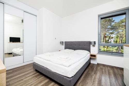 a bedroom with a bed and a large window at Baltic Apartments in Pobierowo