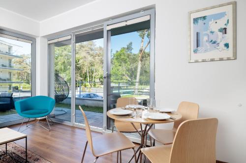 a dining room with a table and chairs and a large window at Baltic Apartments in Pobierowo