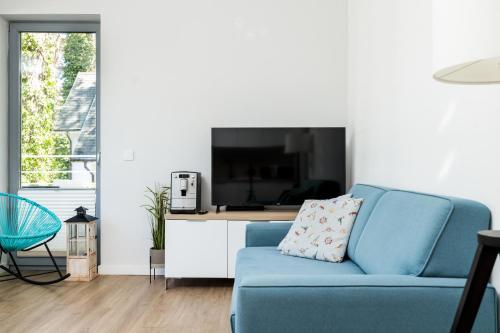 a living room with a blue couch and a tv at Baltic Apartments in Pobierowo