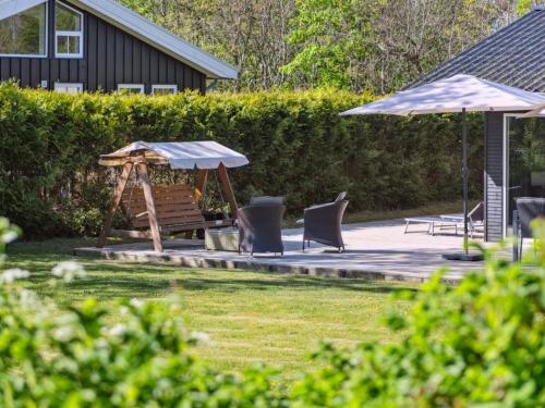 a park with a bench and an umbrella and chairs at Holiday Home Keti - 50m from the sea in NE Jutland by Interhome in Hadsund