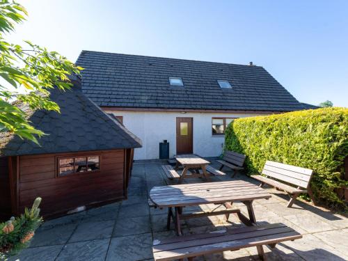 a patio with two picnic tables and a building at Villa Craigmore Lodge by Interhome in Aviemore