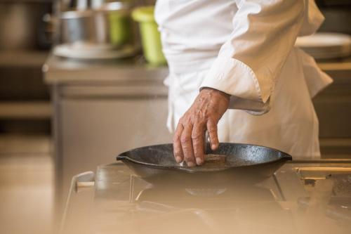 a chef is holding a pan in a kitchen at Hotel & Bildungszentrum Matt in Schwarzenberg