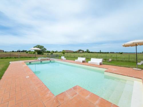 uma piscina com um pátio e um guarda-sol em Apartment Il Grifone-3 by Interhome em Cortona
