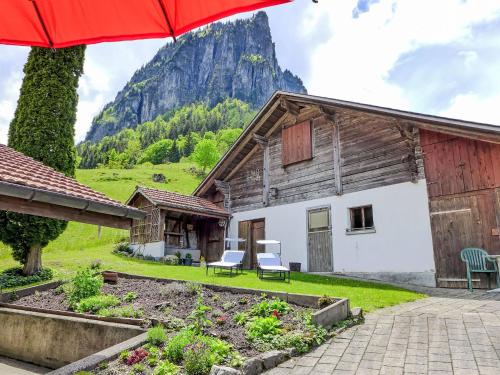 a house with two chairs and a red umbrella at Apartment Engelhorn by Interhome in Innertkirchen