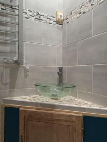 - un lavabo dans la salle de bains avec un bol en verre vert sur un comptoir dans l'établissement CHARMANT STUDIO à 2 pas de NAVAL GROUP au coeur d une rue commerçante, à Cherbourg en Cotentin