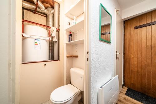 uma pequena casa de banho com um WC e uma porta de madeira em Les Avenières em Châtel