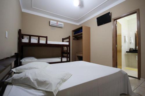 ein Schlafzimmer mit zwei Etagenbetten und einem Fernseher in der Unterkunft Pousada 3 Reis in Olímpia