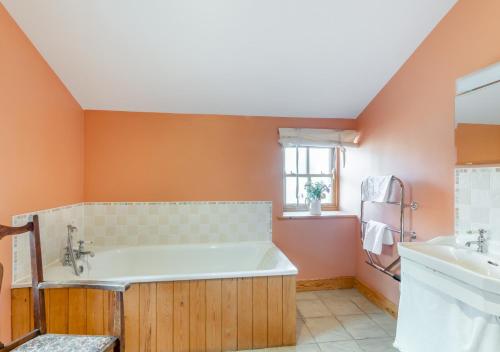 a bathroom with a tub and a sink at St. Coombs Farmhouse in Holy Island