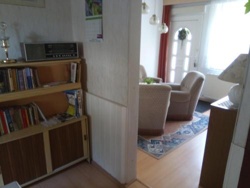 a living room with a book shelf and a couch at Pension Heike in Schönebeck