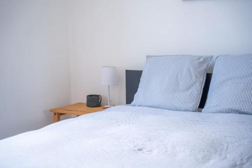 - un lit blanc avec deux oreillers bleus et une table dans l'établissement Bel appartement à 50m de la Grande Plage, à Les Sables-dʼOlonne