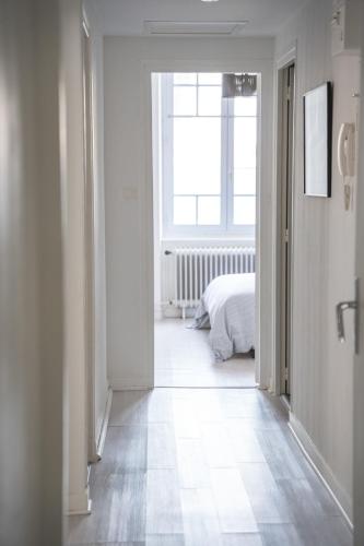 - un couloir blanc avec un lit et une fenêtre dans l'établissement Bel appartement à 50m de la Grande Plage, à Les Sables-dʼOlonne