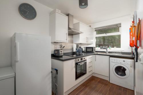 een keuken met witte kasten en een wasmachine en droger bij K Suites - Station Road in Hinckley