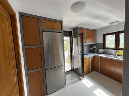 a kitchen with wooden cabinets and a stainless steel refrigerator at Πυργοσπιτο Χαντζακου in Gythio