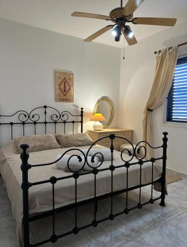 Schlafzimmer mit einem schwarzen Bett und einem Deckenventilator in der Unterkunft Pafia A in Paphos City
