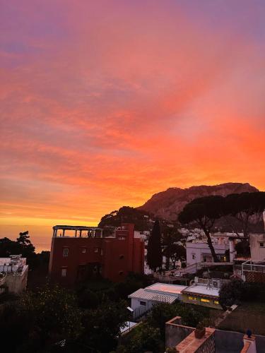 una puesta de sol sobre una ciudad con una montaña en el fondo en Capri Joy, en Capri