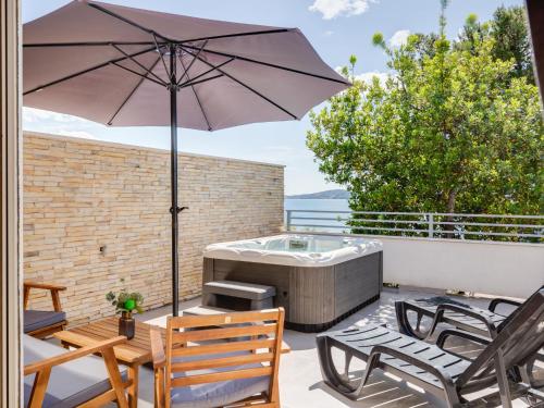 eine Terrasse mit einem Sonnenschirm und einem Whirlpool in der Unterkunft Apartment Gavun by Interhome in Bibinje
