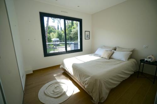 une chambre avec un grand lit avec une grande fenêtre dans l'établissement Villa luxe californienne - Piscine Poolhouse, à Antibes