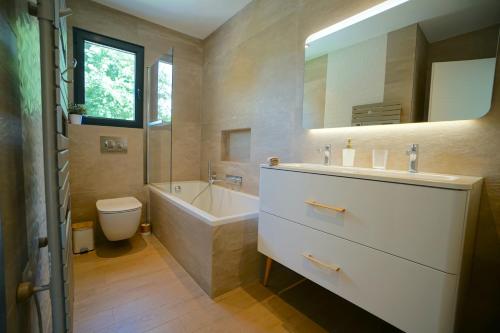 une salle de bain avec un lavabo, une baignoire et des toilettes dans l'établissement Villa luxe californienne - Piscine Poolhouse, à Antibes