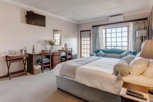 Schlafzimmer mit einem großen Bett, einem Schreibtisch und einem Fenster in der Unterkunft Garden Route Ilita Lodge in Groot Brak Rivier