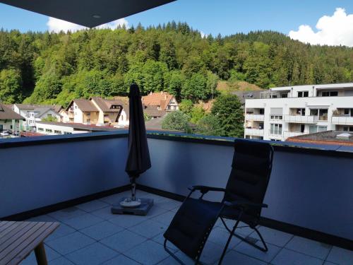 einen Regenschirm und zwei Stühle auf einem Balkon mit Aussicht in der Unterkunft Ferienwohnung Sternenblick in Schönau im Schwarzwald