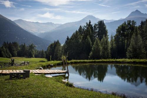 a bench next to a lake with mountains in the background at Tiefhof in Nauders