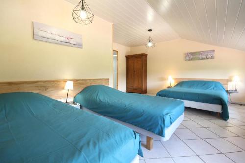 dwa łóżka w pokoju z niebieską pościelą w obiekcie Le champ Vert 