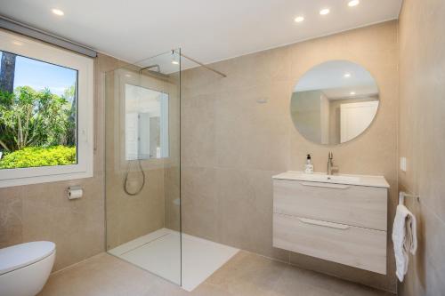 een badkamer met een douche, een toilet en een spiegel bij Villa Ensueño in Cala Ratjada