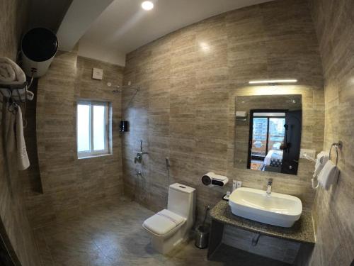 un bagno con lavandino, water e specchio di Asura hotel a Thimphu