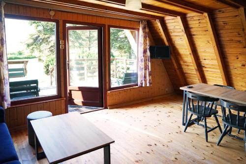 ein Raum mit Tisch und Stühlen und Fenstern in der Unterkunft The Rainbow - Domki Letniskowe in Dźwirzyno