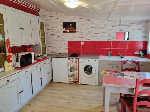 une cuisine avec des armoires blanches et une machine à laver dans l'établissement Maison avec jardin clos et barbecue à Vendat, à Vendat