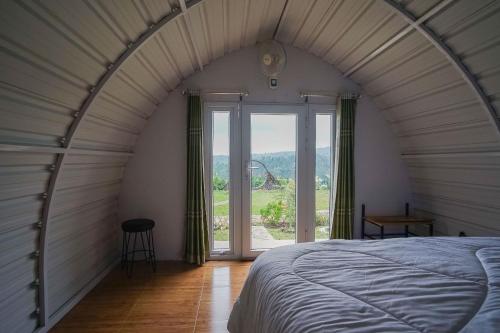 Bett in einem Zimmer mit einem großen Fenster in der Unterkunft Rainbow Glamping in Padangan