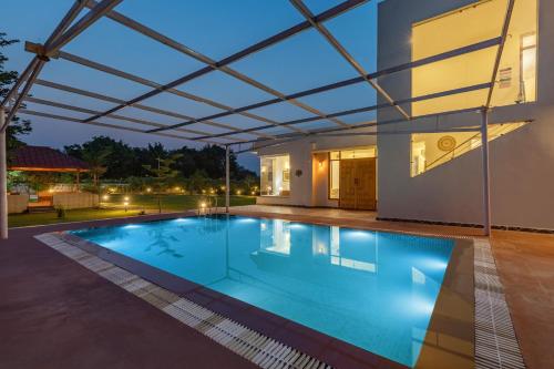 a swimming pool under a roof of a house at Alaya Stays Raga 2BHK Farmstay with an entertainment lounge in Sohna