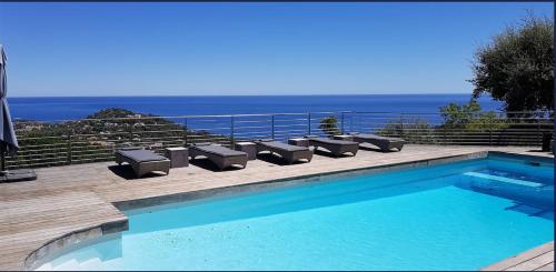 une piscine avec des chaises et l'océan en arrière-plan dans l'établissement Villa luxueuse moderne avec piscine & récemment rénovée, vue mer exceptionnelle!, à Cavalaire-sur-Mer