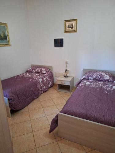 a bedroom with two beds and a table with a lamp at Casa vacanze Bouganville in Gonnosfanàdiga