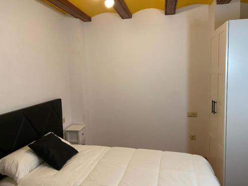 a bedroom with a white bed with a black pillow at Casa Rural La Peña in Mirambel