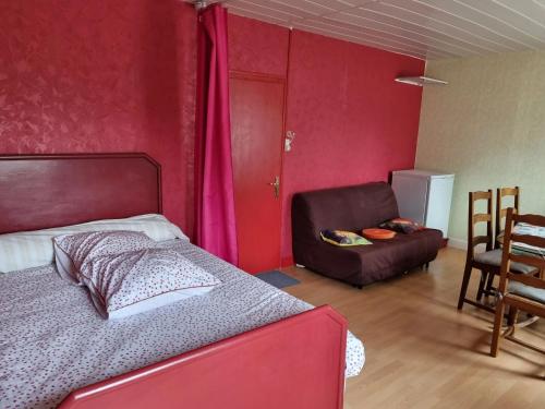 - une chambre avec des murs rouges, un lit et une chaise dans l'établissement Maison avec jardin clos et barbecue à Vendat, à Vendat