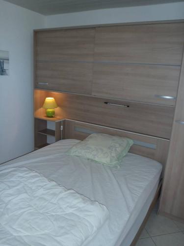 une chambre avec un lit blanc avec une tête de lit en bois dans l'établissement APPT 3 PCES MEZ 45m2 et TERRASSE 7m2 REF4000, à Le Castellas