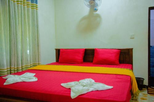 a red bed with two towels on top of it at Sri Shahrukh Lake Resort in Tissamaharama