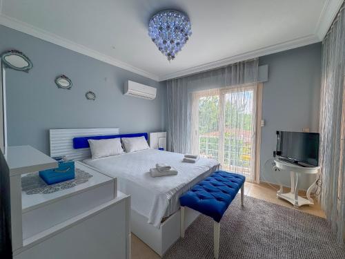 a bedroom with a bed with a blue stool and a television at Villa Siesta Kusadasi in Kuşadası