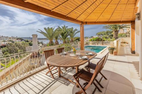a patio with a table and chairs on a balcony at Azure Dream: Lux 4-Bed Villa with Pool, Sea View & Garage in Mellieħa