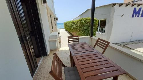 a wooden table and chairs on a balcony with the ocean at 30meters from the sea apartment in Larnaca in Voroklini